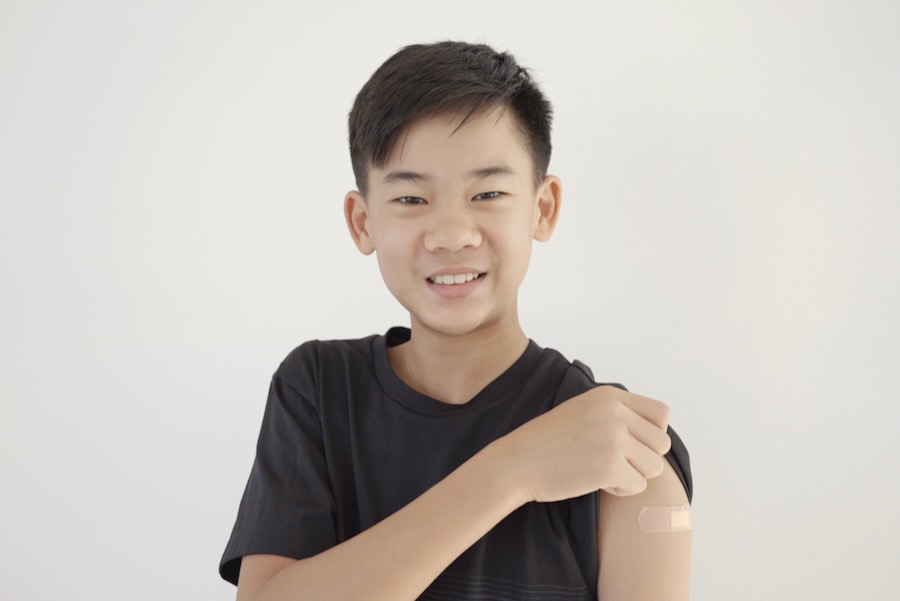 Guardians of Health: The Importance of the HPV Vaccine for Boys Mixed Asian teen boy showing his arm with bandage after being vaccinated